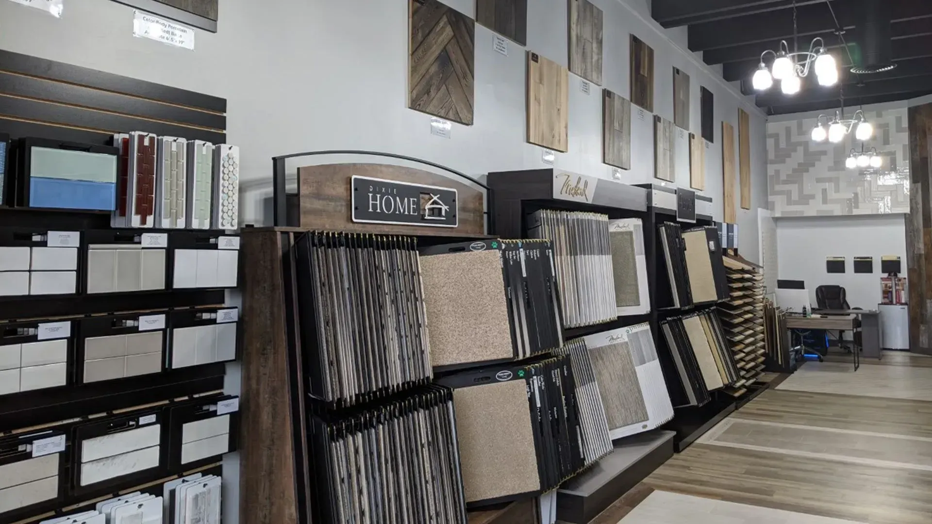 Interior of a tile store, displaying various tile samples on walls and shelving. Beige, brown, and patterned tiles are prominently featured.