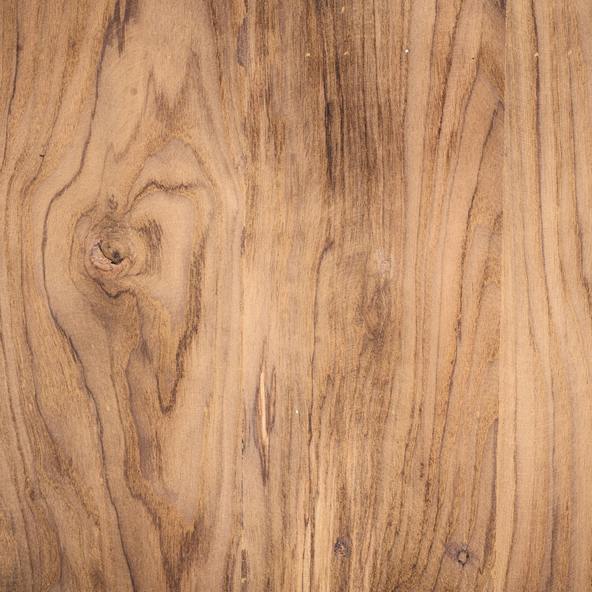 Close-up of brown wood grain with dark lines and a knot.