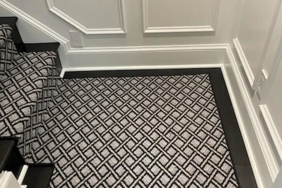 Staircase with patterned carpet and black accents. White trim borders the ceiling and walls.