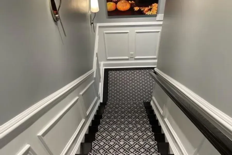 Staircase with gray walls, white molding, and a patterned carpet runner