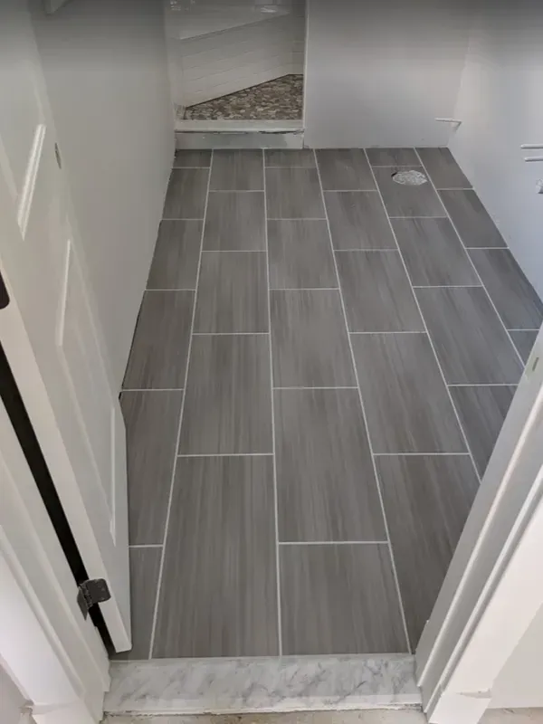 Gray tiled entryway with white door frames. Tiles are rectangular and have light gray grout.