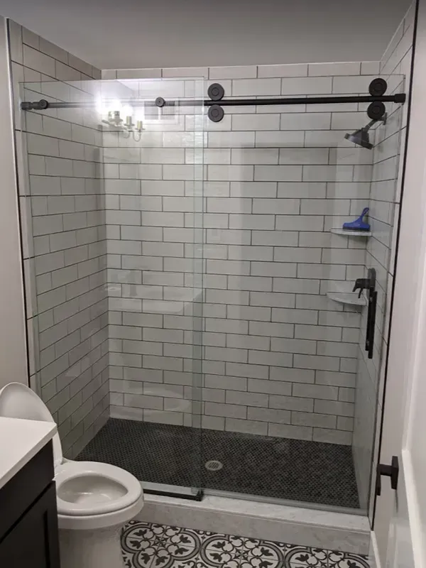 Modern bathroom with a tiled shower, a toilet, and a patterned floor