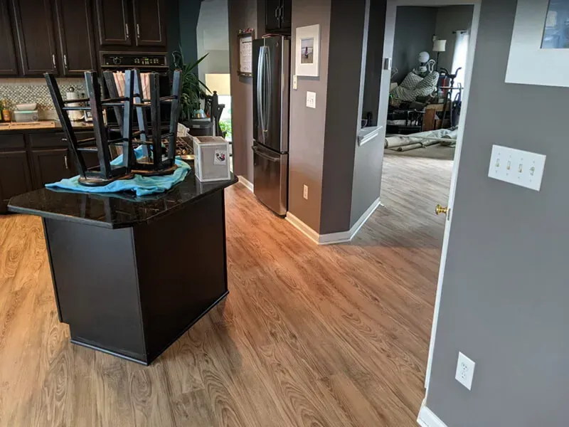 Kitchen with dark cabinets, island with stools flipped over, and new wood flooring.