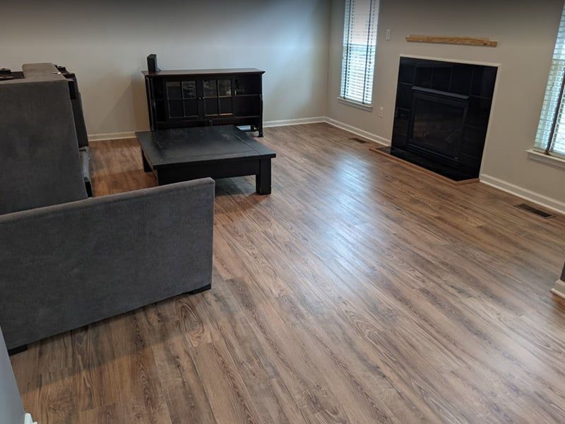 Living room with dark furniture, including a cabinet, coffee table, and fireplace. Wood-look flooring.