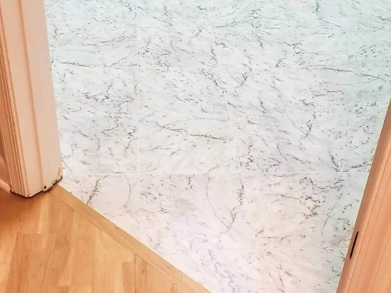 Wooden floor meets marble-patterned flooring in an open doorway.