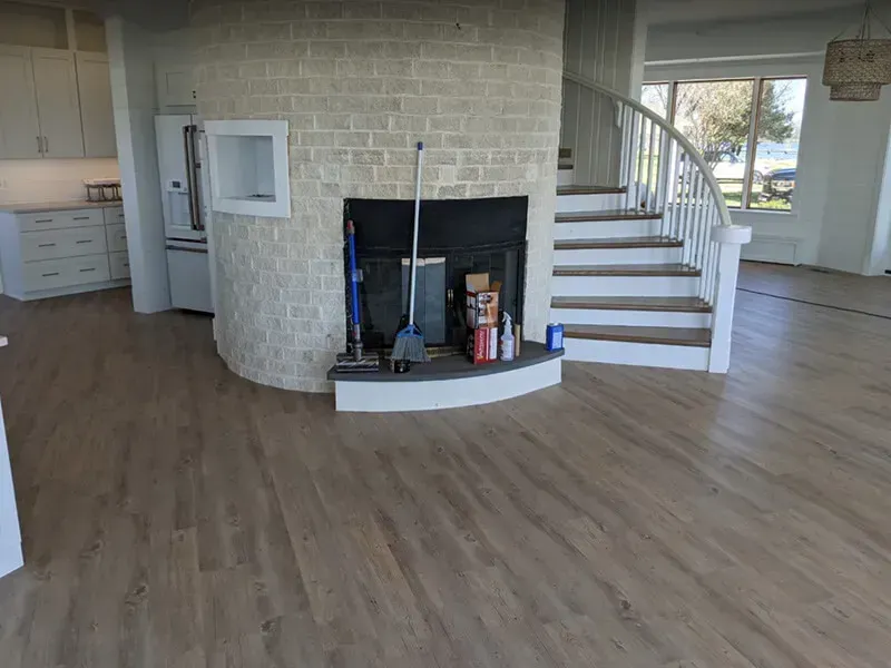 Interior view of a home with wood-look flooring, a brick fireplace, and a curved staircase