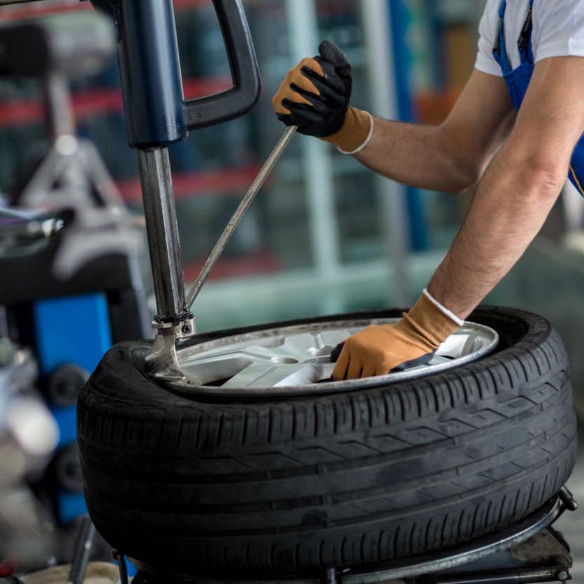 Mechanic changing a tire, using a machine in a garage.