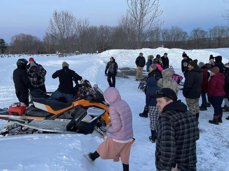 a group of people standing around a snowmobile