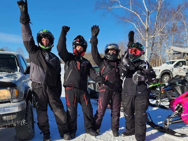 a group of snowmobile riders are posing for a picture with their arms in the air