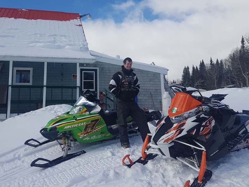 a man stands next to snowmobiles