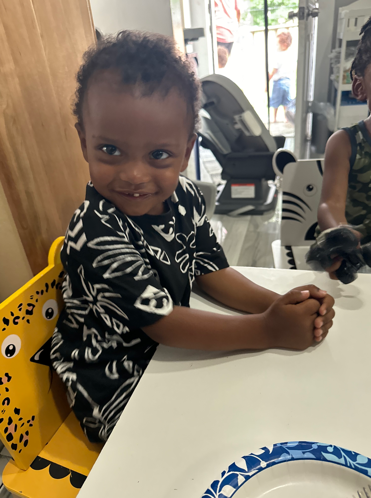 A little boy is sitting at a table with his hands folded