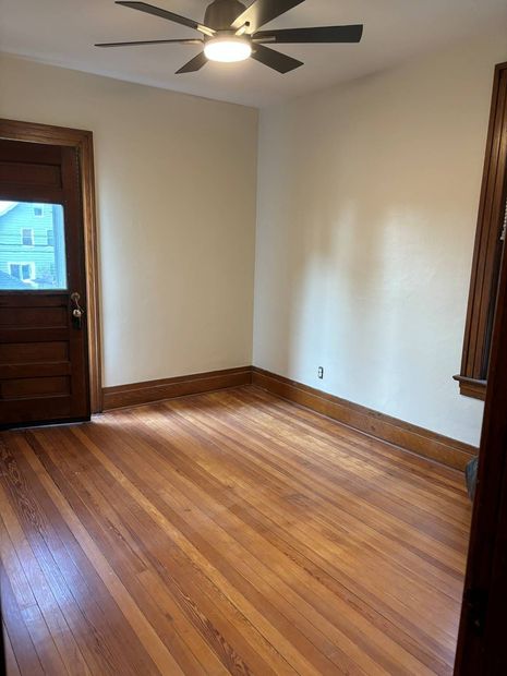 An empty room with hardwood floors and a ceiling fan.