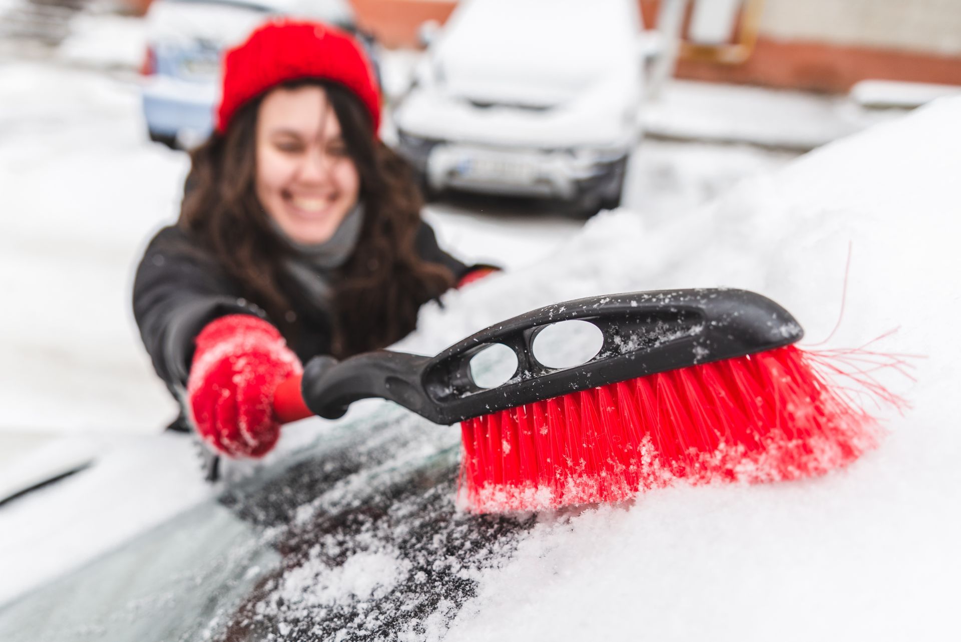 A woman is cleaning her car with a red brush.