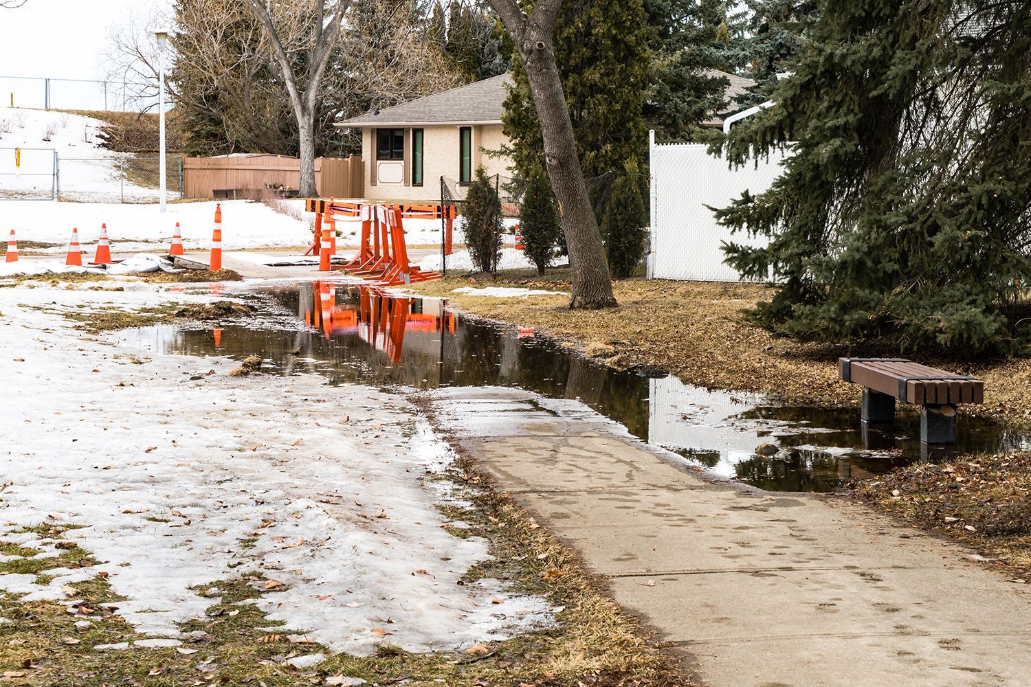 A puddle of water is sitting on a sidewalk next to a house.