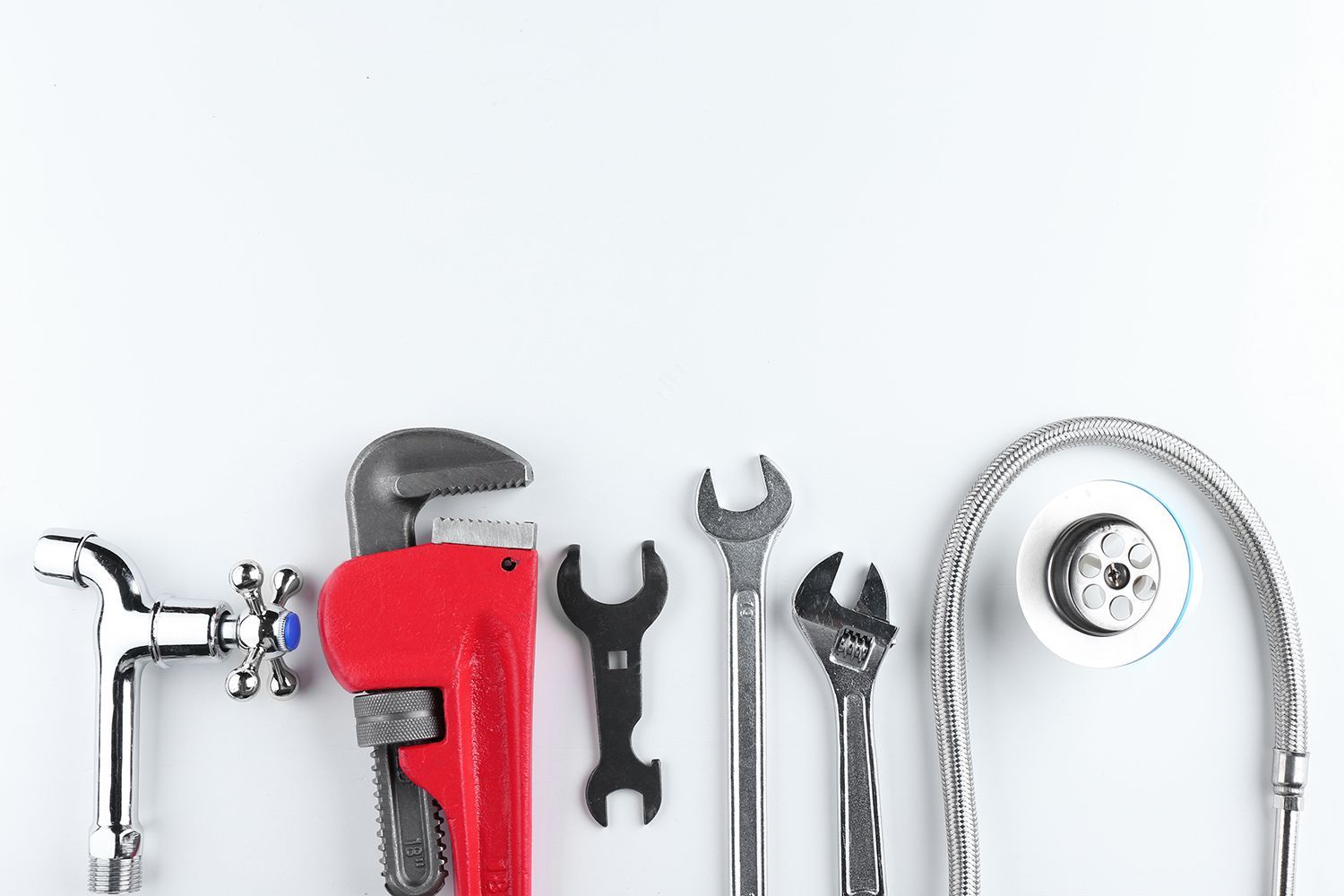 A bunch of plumbing tools are lined up on a white surface.