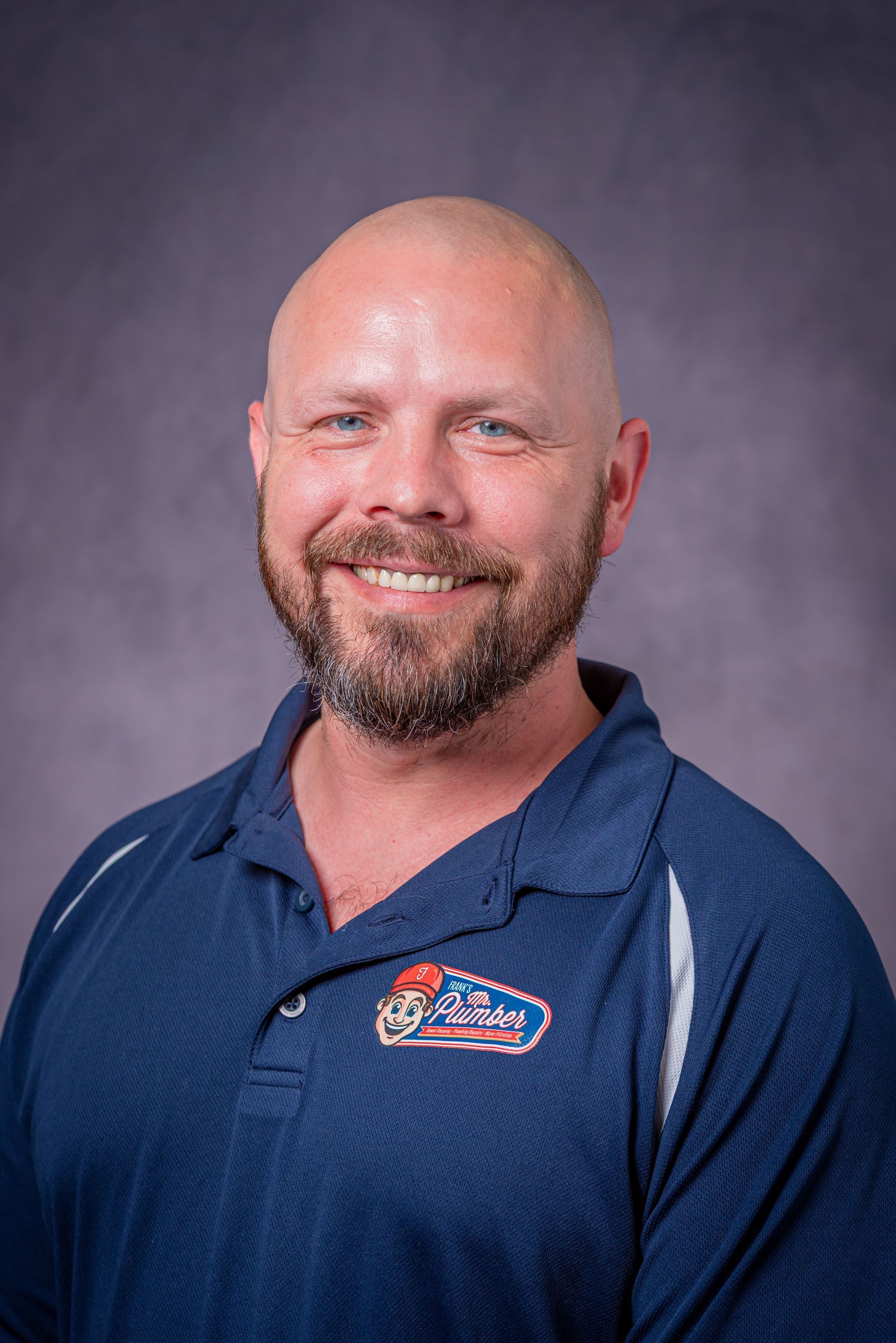 A man in a blue shirt is smiling for the camera.