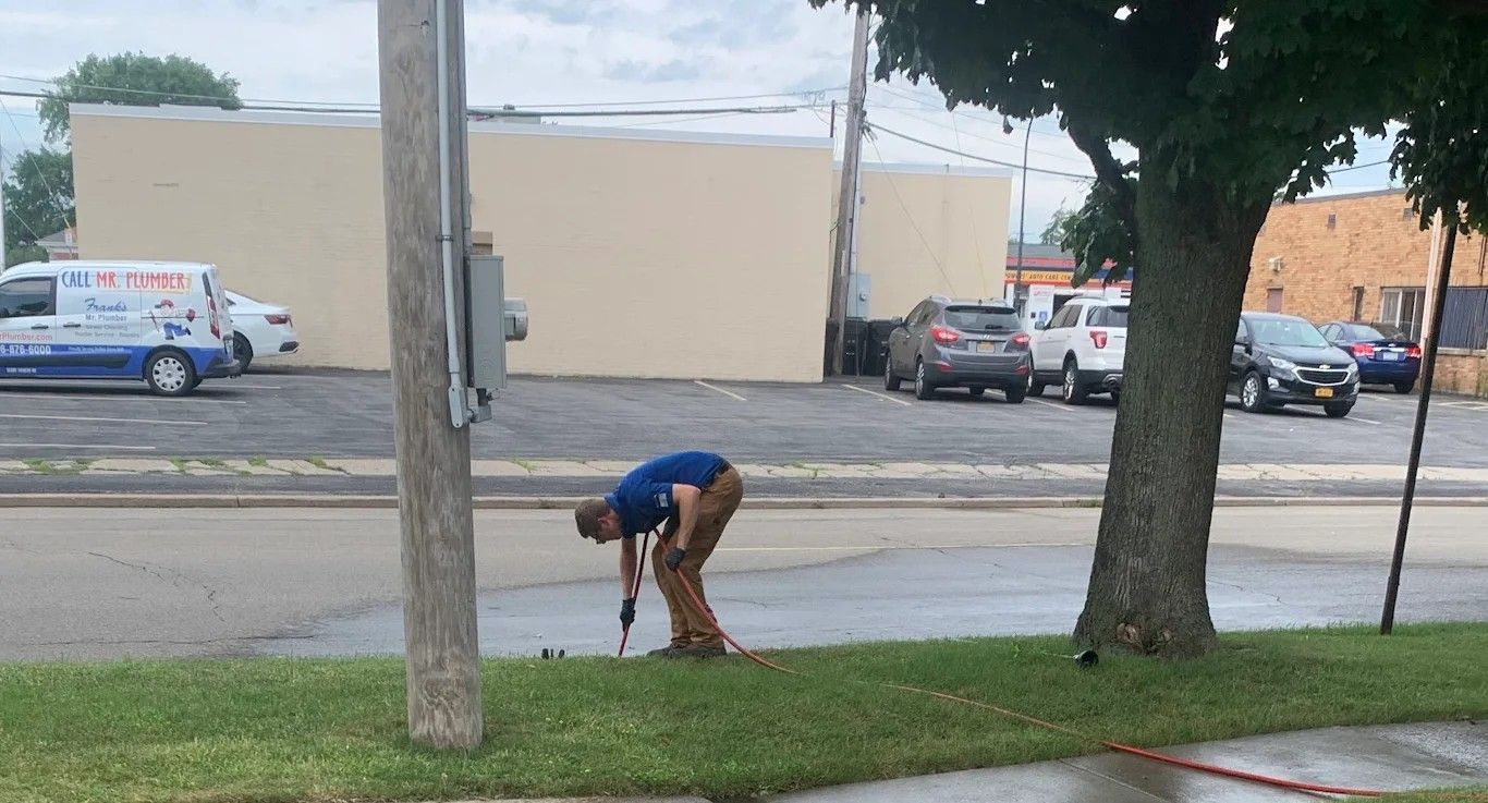 A man is bending over in the grass with an umbrella.