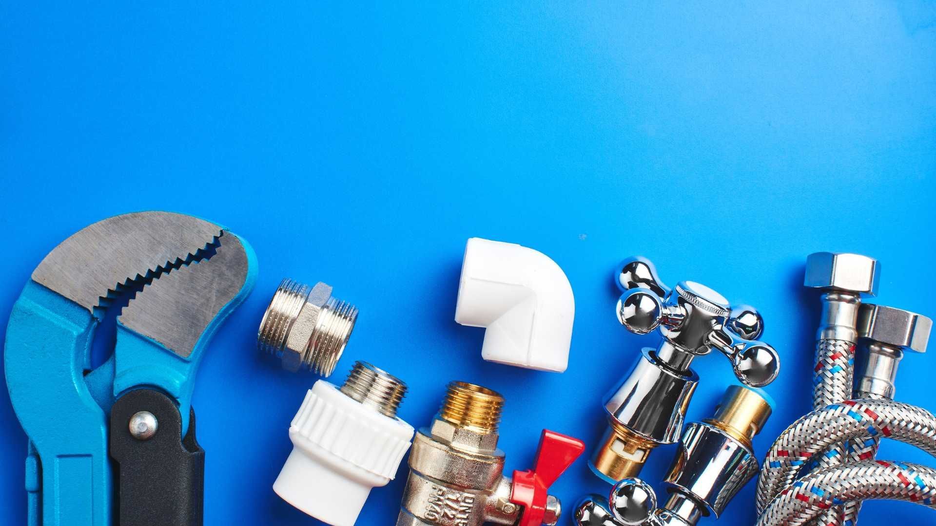 A wrench , pipe fittings , and a hose on a blue background.