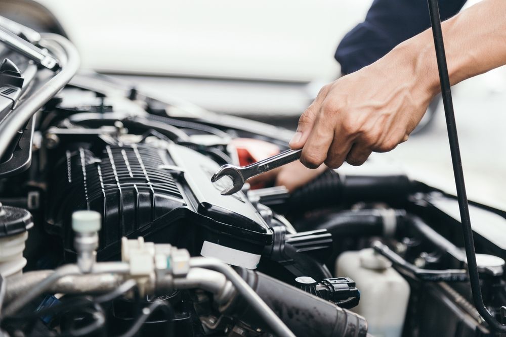 A Man is Working on the Engine of a Car With a Wrench — Auto Blue Service Centre In Bungalow, QLD