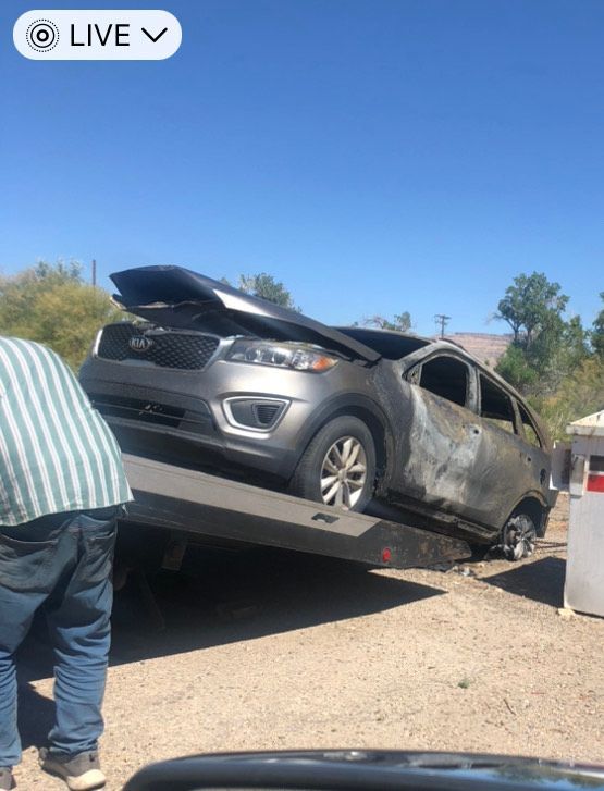 A damaged gray SUV is being towed; smoke damage is visible.