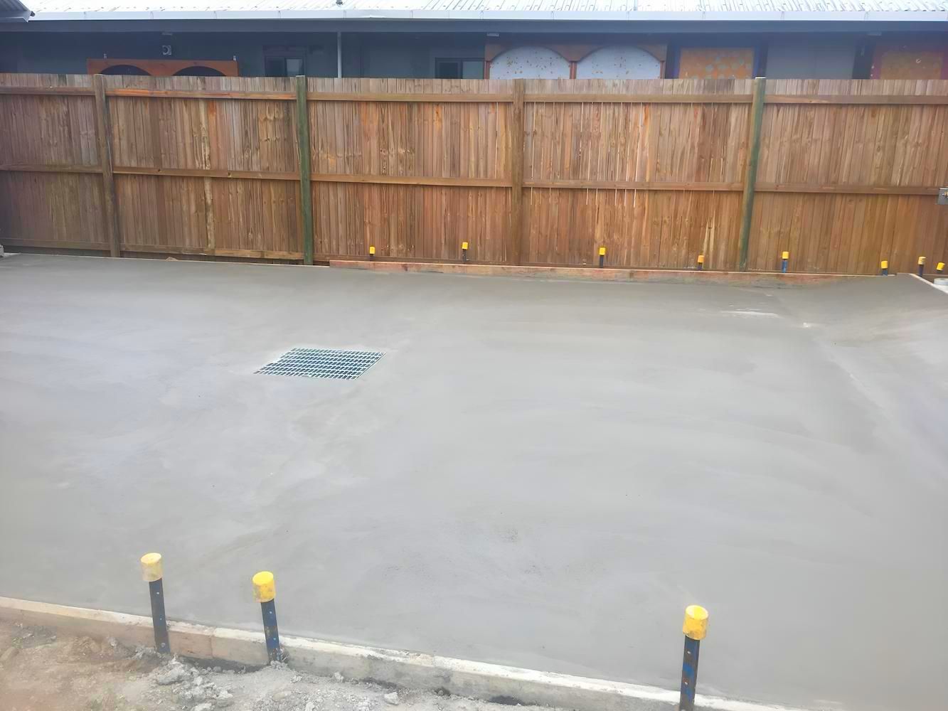 A Concrete Driveway With A Wooden Fence In The Background — Tropical North Concreting In Trinity Park, QLD