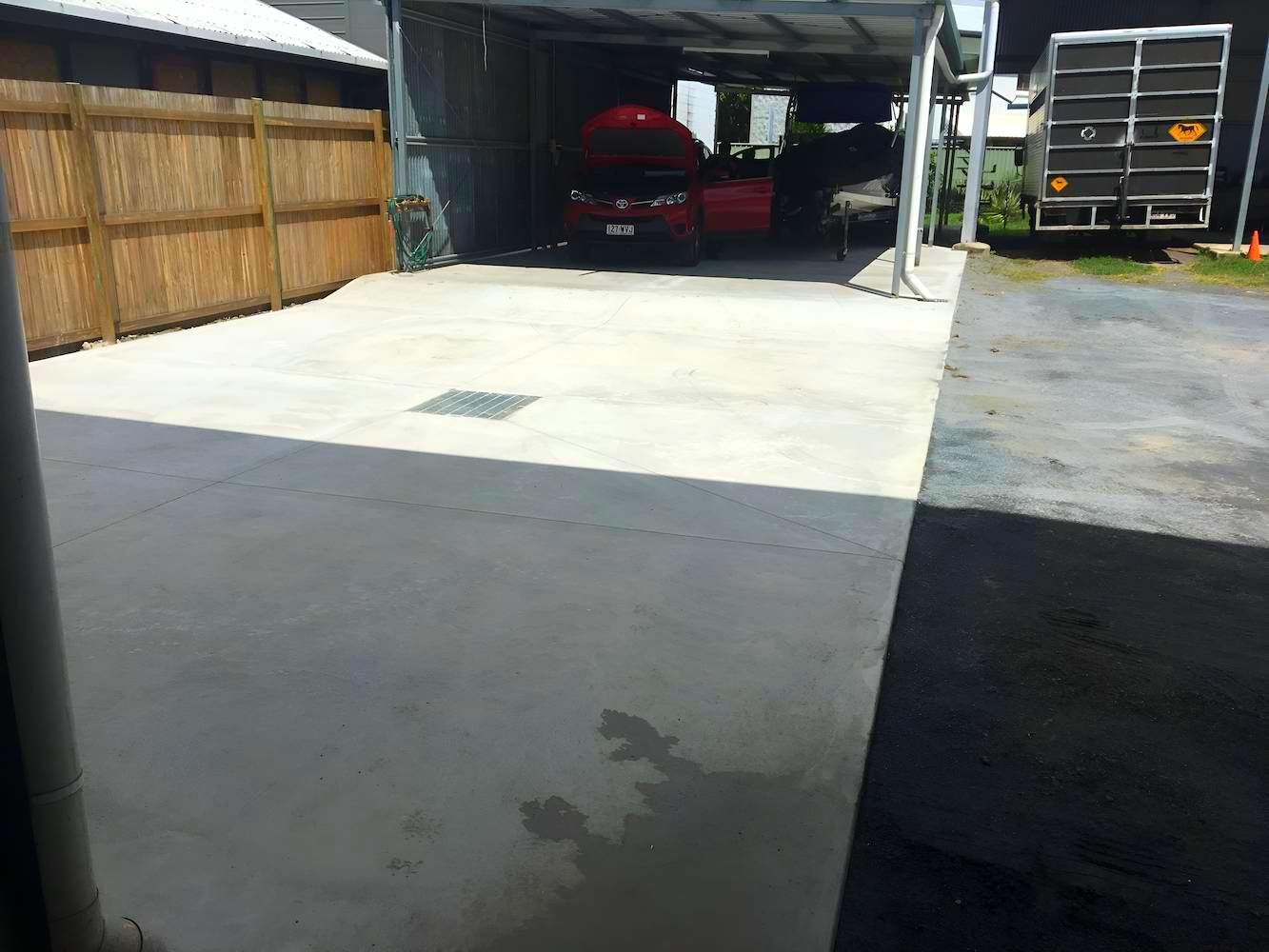 A Red Car Is Parked Under A Canopy In A Driveway — Tropical North Concreting In Trinity Park, QLD