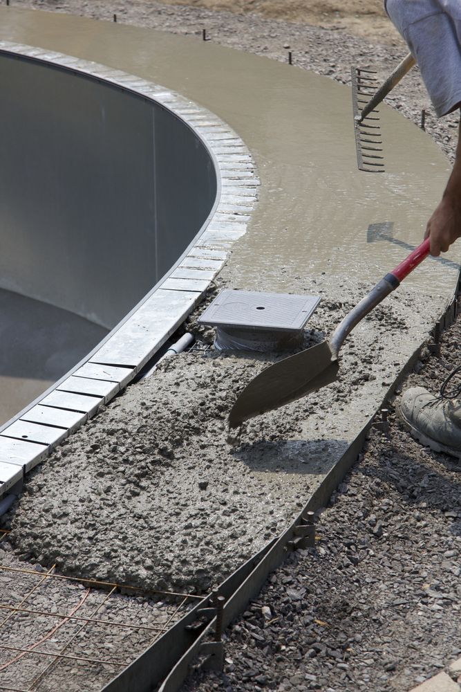 A Person Is Using A Shovel To Mix Concrete Near A Pool — Tropical North Concreting In Trinity Park, QLD