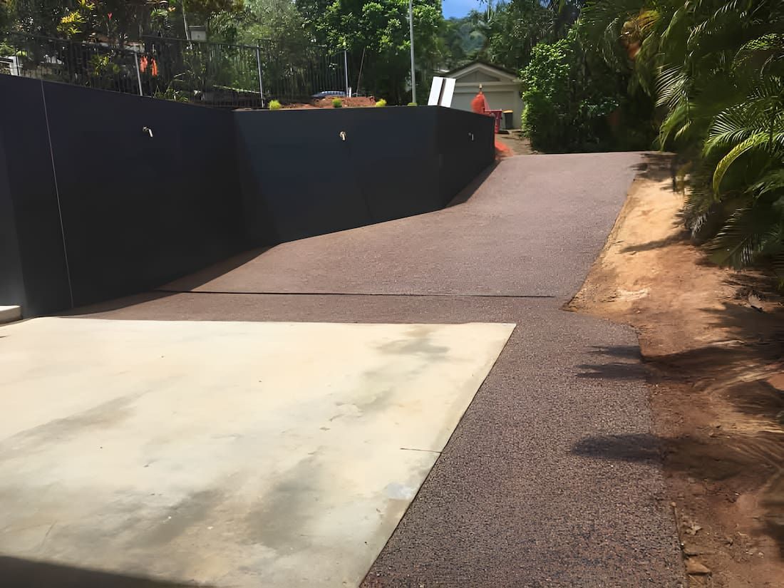 A Driveway With A Concrete Curb And A Fence On The Side Of It — Tropical North Concreting In Trinity Park, QLD