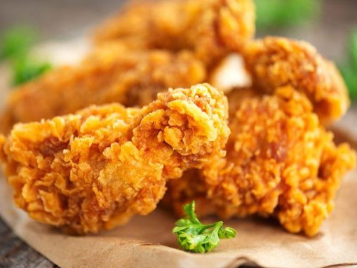 A close up of fried chicken on a piece of paper on a table.