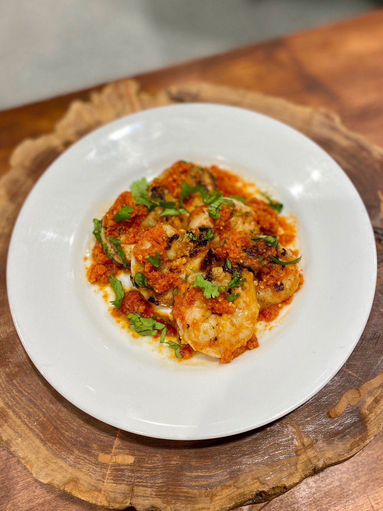 A white plate topped with shrimp and tomato sauce on a wooden table.