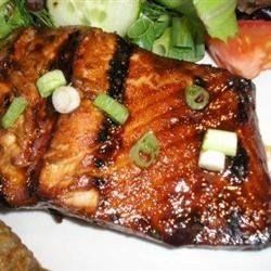 Grilled salmon fillet with glaze and chopped scallions, served with salad.