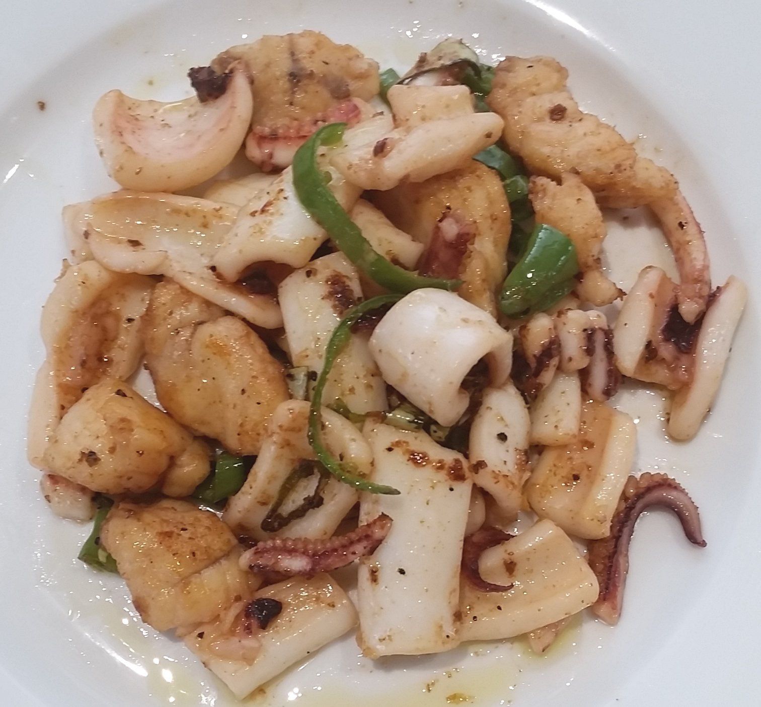 Sautéed calamari with green peppers on a white plate.