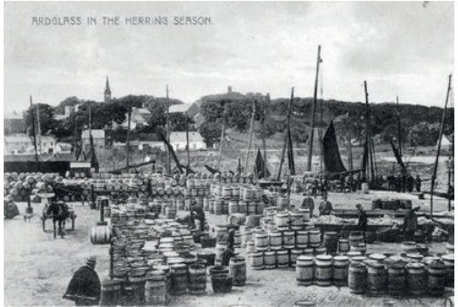 Redress harbor scene with barrels, boats, and figures, likely a bustling herring season.
