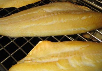Smoked fish fillets, light brown, on a wire rack.