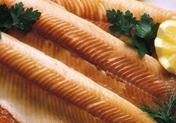 Smoked fish fillets, arranged closely, with parsley and lemon garnish.