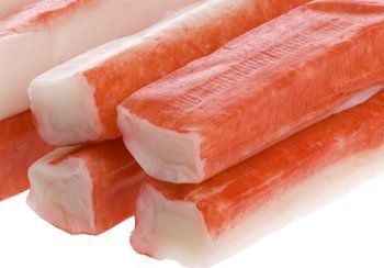 Close-up of several bright red and white crab sticks, stacked slightly.