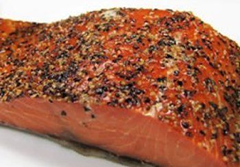 Smoked salmon fillet, reddish-orange color with a dark, speckled seasoning.