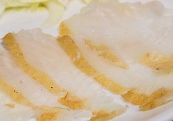 Slices of white fat with yellow layers, possibly lard or bacon, on a plate.