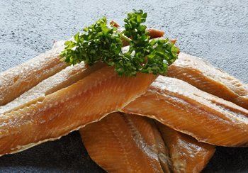 Smoked fish fillets, brown, with parsley garnish.