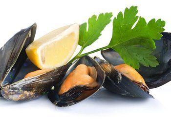 Steamed mussels with lemon wedge and parsley garnish.