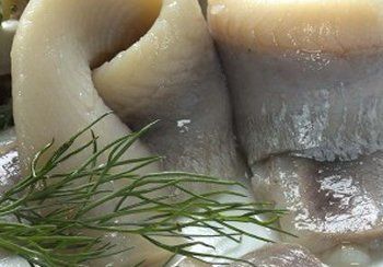Pickled herring with dill garnish.