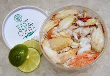 Container of crab meat, with a lime and slices beside it, and the container’s lid off.