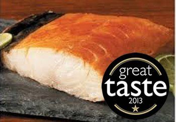 Smoked fish fillet with a “Great Taste 2013” award sticker, on a dark slate board.