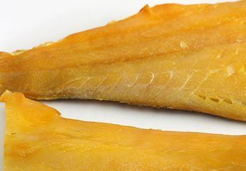 Smoked fish fillets, golden brown, on a white surface.