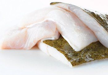 Halibut fillets, white and beige, stacked on a white surface.