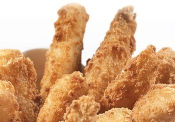 Close-up of golden, fried food items, possibly chicken or mozzarella sticks, in a container.