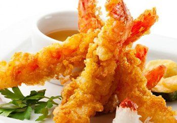 Tempura shrimp with dipping sauce and parsley garnish.