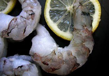 Raw shrimp arranged near lemon slices.