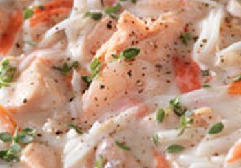 Salmon and pasta in creamy white sauce, garnished with herbs and pepper.