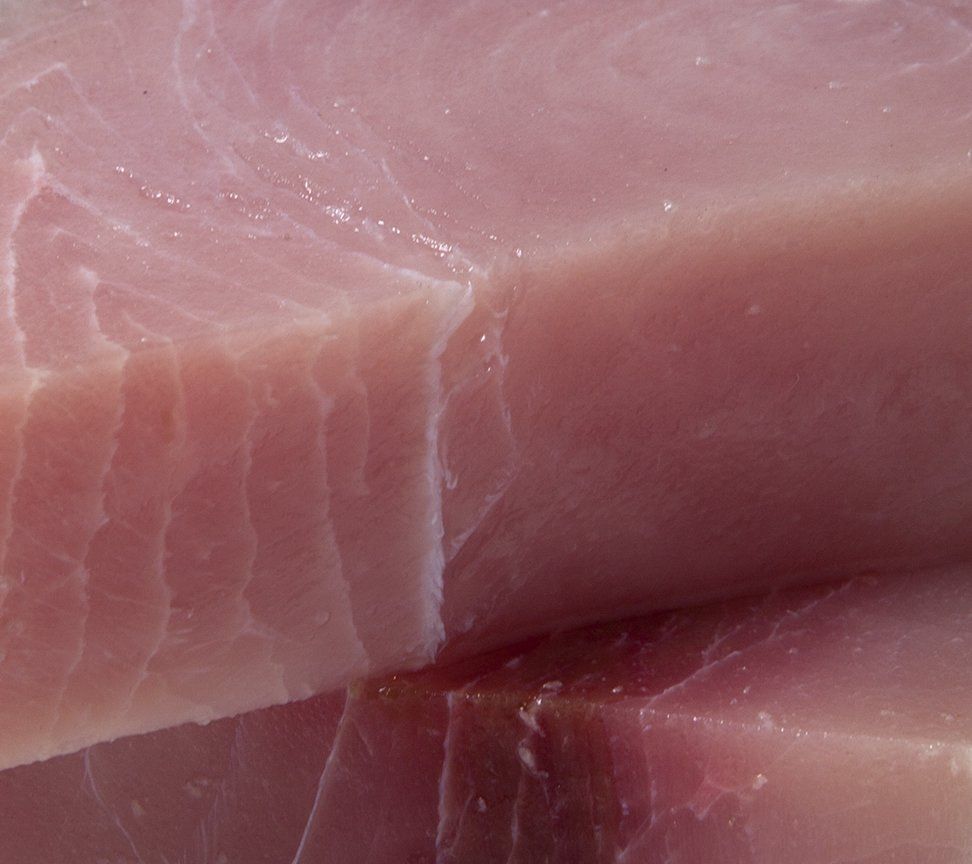 Close-up of raw fish fillets, pale pink with visible striations.